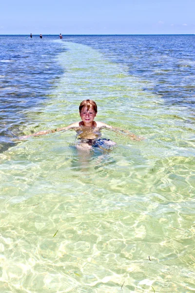 Chlapec v oceánu plave v krásné čisté vodě — Stock fotografie
