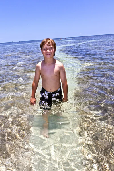 Chlapec v oceánu stojí v krásné čisté vodě — Stock fotografie