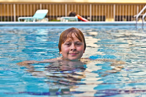 Jongen geniet zwemmen in een buitenzwembad — Stockfoto