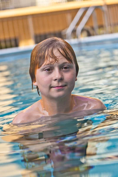 Menino gosta de nadar em uma piscina exterior — Fotografia de Stock