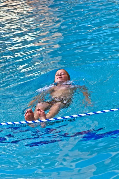 Menino gosta de nadar em uma piscina exterior — Fotografia de Stock
