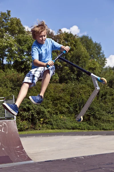 Young boy going airborne with his scooter — Stock Photo, Image