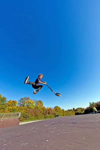 Ребенок летит по воздуху на скутере — стоковое фото
