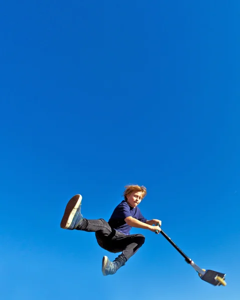 Ребенок летит по воздуху на скутере — стоковое фото