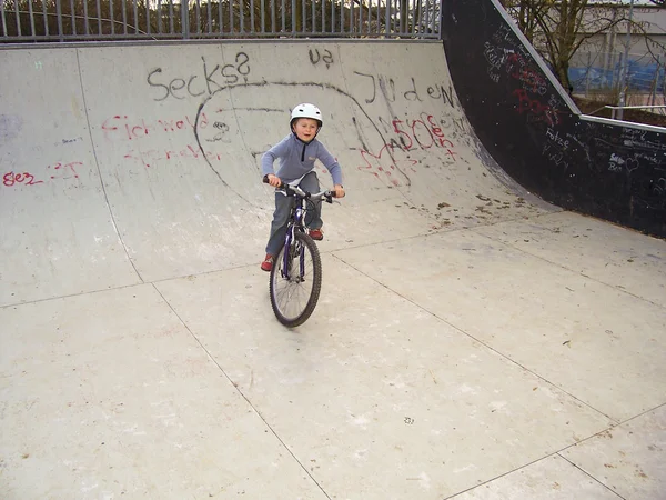 Joung男孩与他的山地自行车火车BMX技巧在半pip — 图库照片