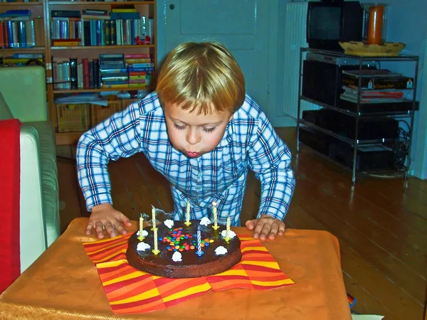 Menino apaga suas velas de aniversário em seu aniversário — Fotografia de Stock