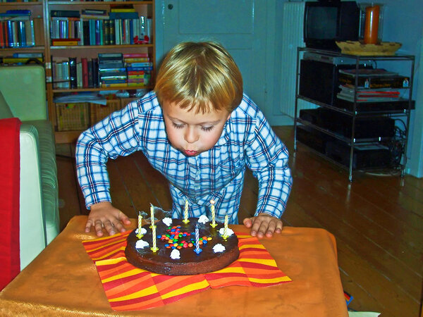 Boy blows out his birthday candles at his birtday
