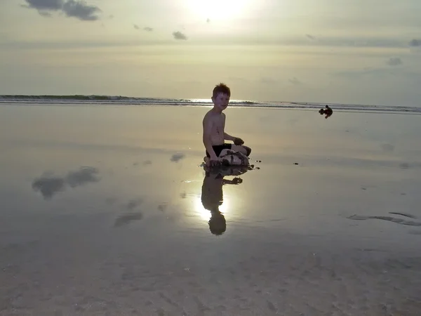 Хлопчик на пляжі з заходом сонця і роздуми — стокове фото