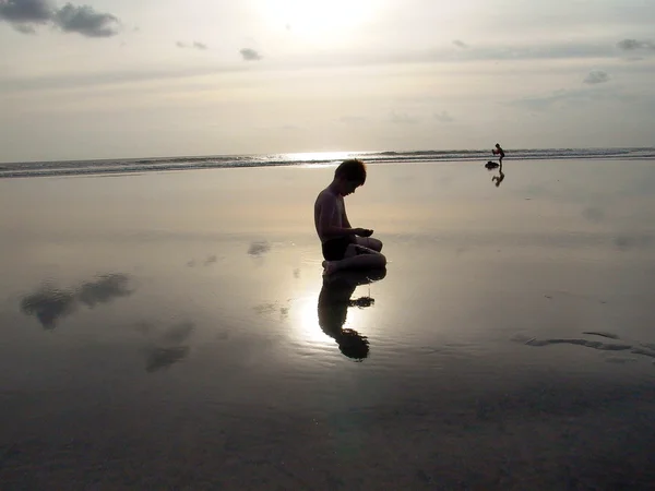 Αγόρι στην παραλία με το ηλιοβασίλεμα και αντανακλάσεις — Φωτογραφία Αρχείου