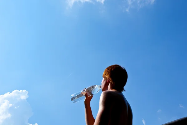 Young boy drinks water out of a bottle — Stock Photo, Image