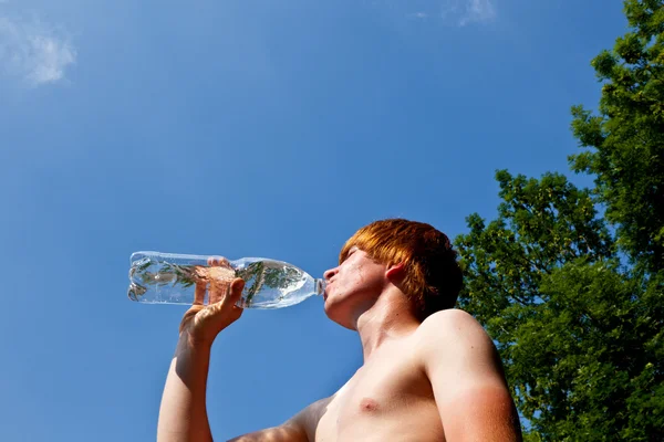 Молодий хлопчик п'є воду з пляшки — стокове фото