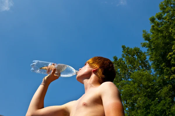 Young boy drinks water out of a bottle — Stock Photo, Image