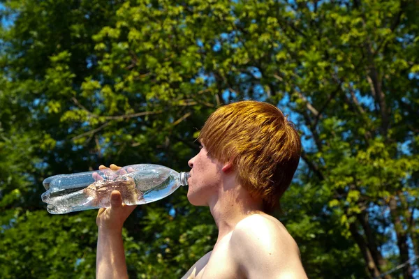 年轻的男孩在喝一瓶水 — 图库照片