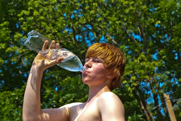 Mladý chlapec pije vodu z láhve — Stock fotografie