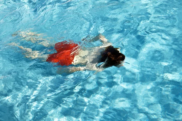 Rapaz feliz está nadando na piscina exterior — Fotografia de Stock