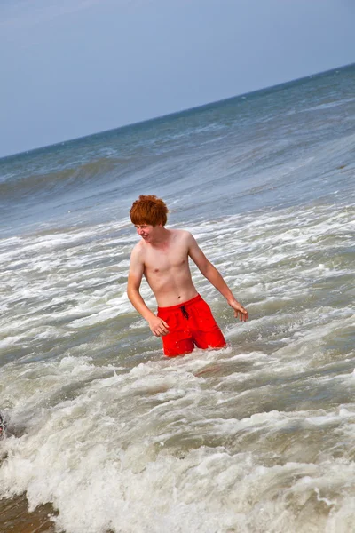 Menino se diverte na praia tempestuosa — Fotografia de Stock