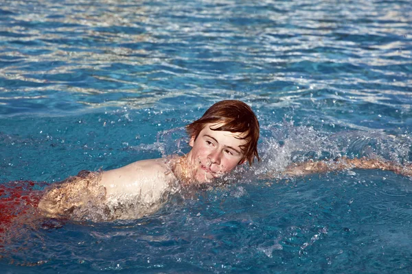 Мальчик ползает в бассейне — стоковое фото