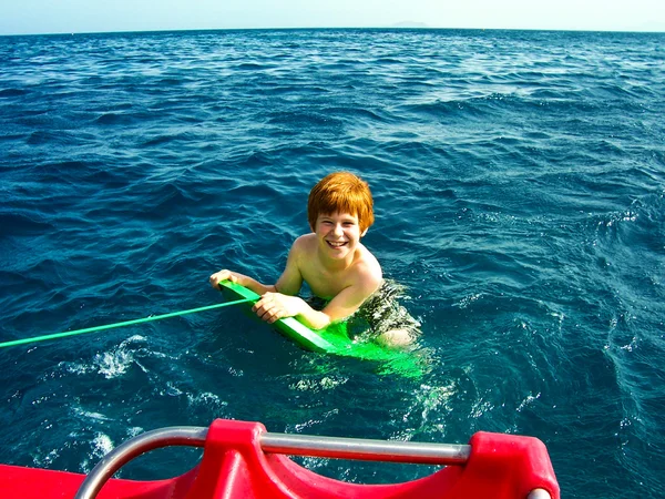 Dragande ett barn på en surfbräda — Stockfoto