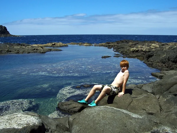 Söt pojke poserar på en klippa — Stockfoto