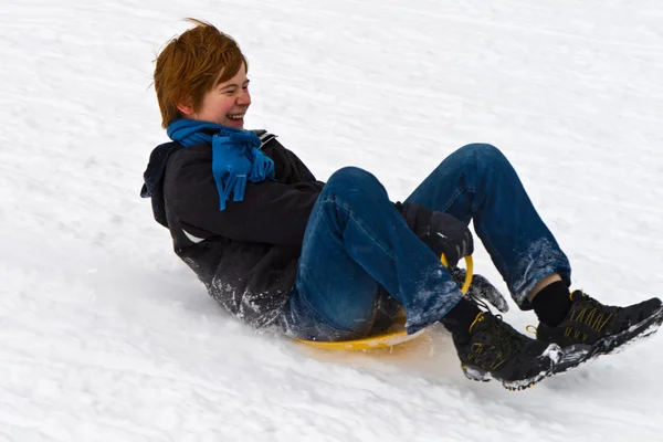 Kinderen zijn rodelen naar beneden de heuvel in de witte sneeuw, winter — Stockfoto