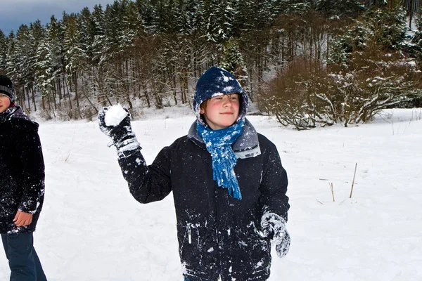 Дети играют в снежки в белом снежном районе — стоковое фото