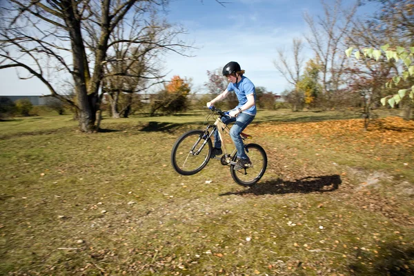 Giovane ragazzo sta cavalcando con il Dirtbike e corse nel paesaggio — Foto Stock