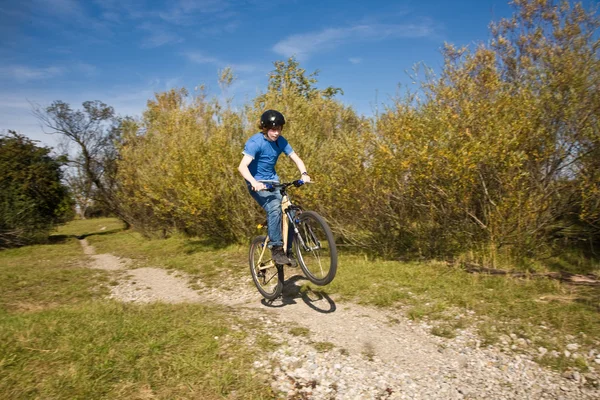 Мальчик едет на грязном велосипеде и гоняет в ландшафте — стоковое фото