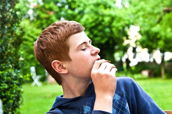 Junge isst ein Brot im Garten — Stockfoto