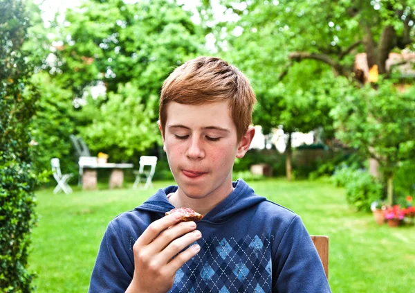 Pojken äta ett bröd i trädgården — Stockfoto
