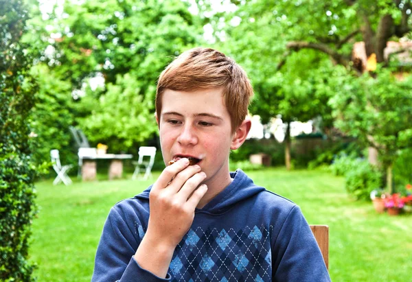 Мальчик ест хлеб в саду — стоковое фото