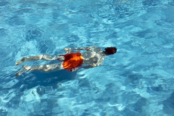 Niño feliz está nadando en la piscina al aire libre — Foto de Stock