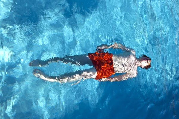 Felice ragazzo sta nuotando nella piscina all'aperto — Foto Stock