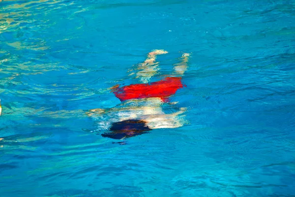 Rapaz feliz está nadando na piscina exterior — Fotografia de Stock