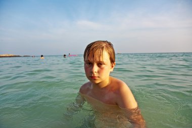 Angry young boy is walking thru the clear warm saltwater at the clipart