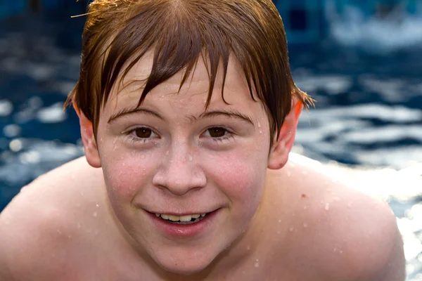 Lächelnder und glücklicher Junge mit roten Haaren schwimmt und entspannt in — Stockfoto
