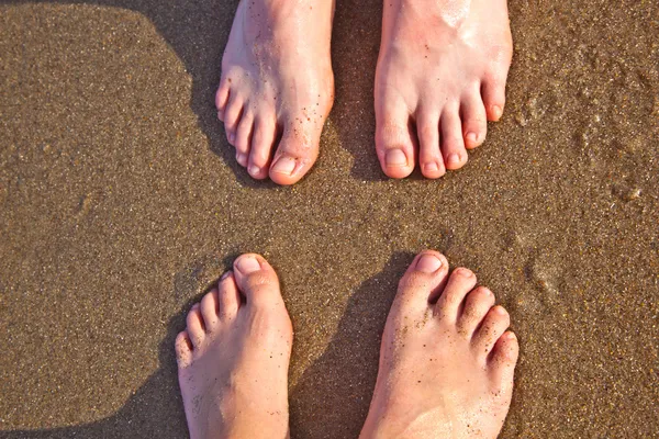 Pies de padre e hijo en la arena mojada de la playa — Foto de Stock