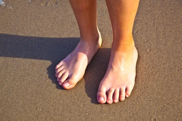 Füße des Jungen auf dem nassen Sand am Strand — Stockfoto