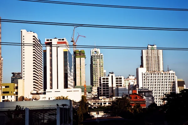 Stromkabel vor Wolkenkratzern und kleinen Häusern in Verbot — Stockfoto