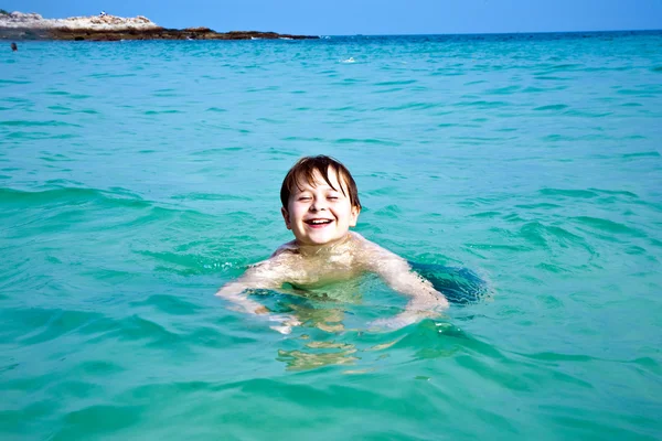 Menino está desfrutando da água morna clara na bela praia, mas — Fotografia de Stock