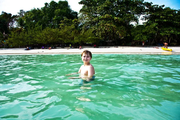 Kluk si užívá jasné teplé vody na krásné pláži, ale — Stock fotografie