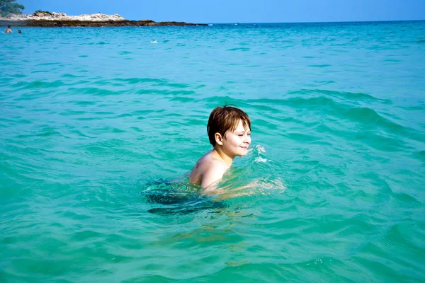 Jongen is genieten van het duidelijk warm water op het prachtige strand maar — Stockfoto