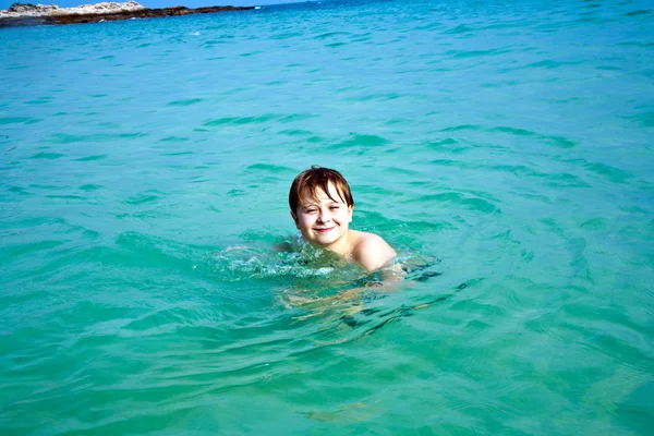 Ragazzo sta godendo l'acqua calda e limpida alla bella spiaggia, ma — Foto Stock