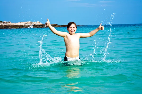 Kluk si užívá jasné teplé vody na krásné pláži, ale — Stock fotografie