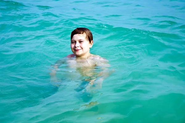Хлопчик насолоджується чистою теплою водою на прекрасному пляжі, але — стокове фото