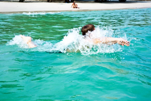 Chico está disfrutando del agua caliente clara en la hermosa playa, pero — Foto de Stock
