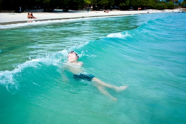 Мальчик наслаждается чистой теплой водой на красивом пляже, но — стоковое фото