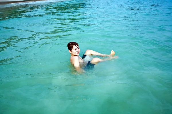 Fiú élvezi a tiszta meleg víz, a gyönyörű tengerparton, de — Stock Fotó
