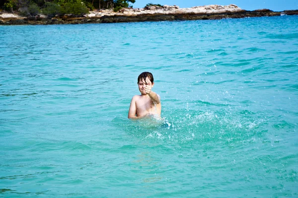 Boy is enjoying the clear warm water at the beautiful beach but — Stock Photo, Image