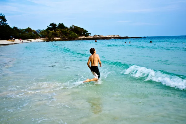 Chico está disfrutando del agua caliente clara en la hermosa playa, pero — Foto de Stock