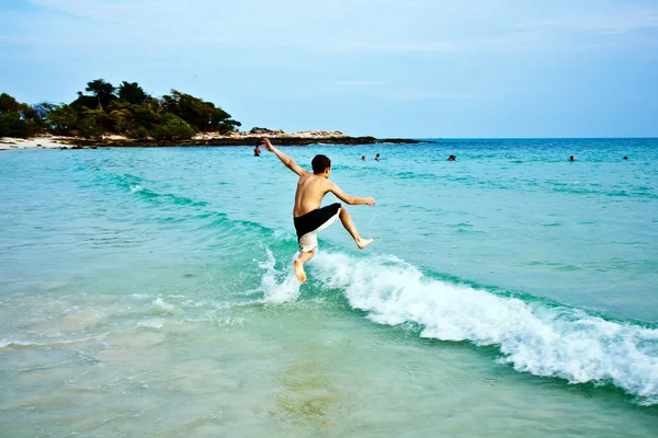 Pojken njuter det klara varma vattnet på den vackra stranden men — Stockfoto